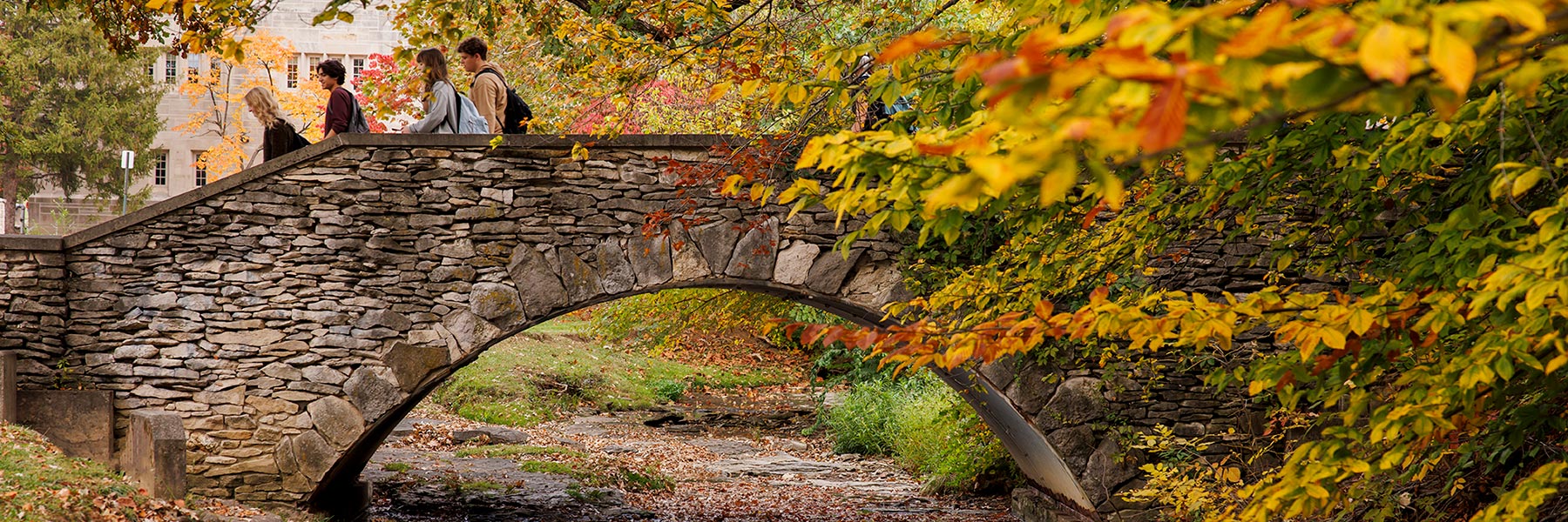 Stone bridge and people over Campus River on the IU Campus